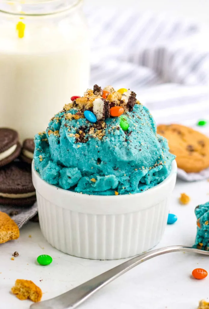 bright blue dessert in a white ramekin, topped with crushed cookies and mini colorful candies