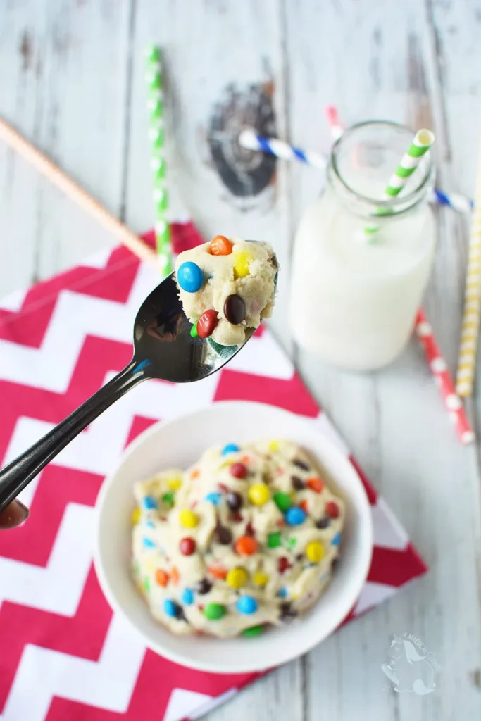 spoonful of m&m cookie dough with a bowl of more m&m dough in the background